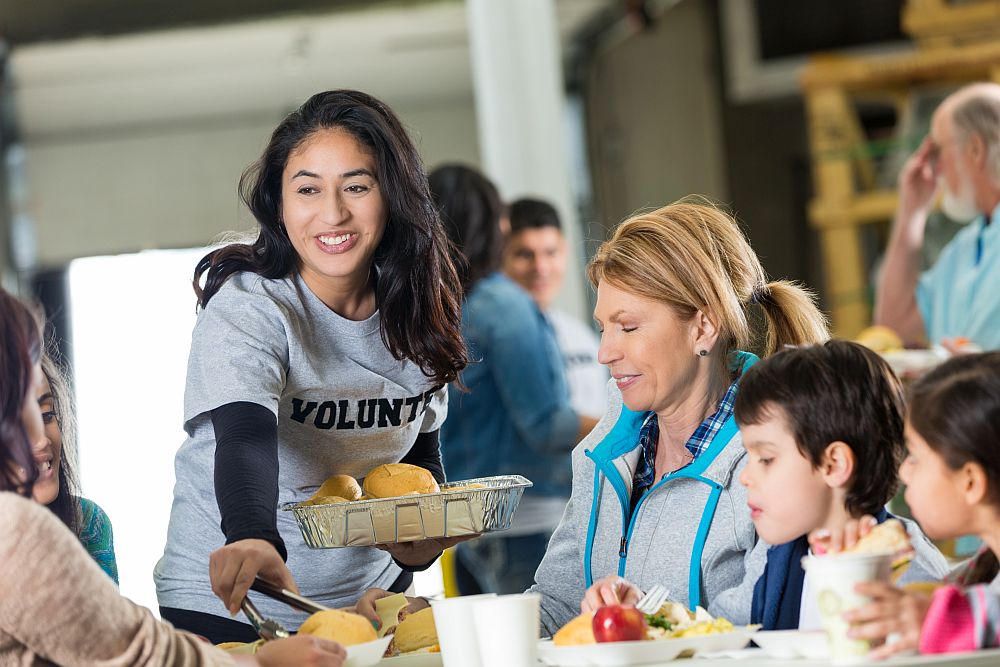 Volunteer serves meal to homeless in shelter